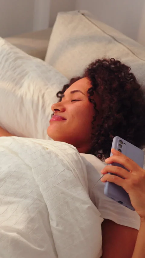 Relaxed woman lying in bed using smartphone in bright modern bedroom Vídeo Stock 324728067