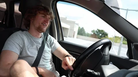 Relaxed young driver enjoys music while driving through the city Stock Footage 343720104