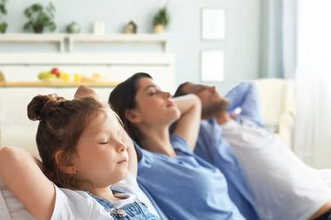 Relaxed young family resting and dreaming about new home on comfortable sofa Stock Photos