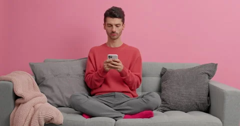 Relaxed young man technology user sits on comfortable sofa browses internet Stock Footage 143624799