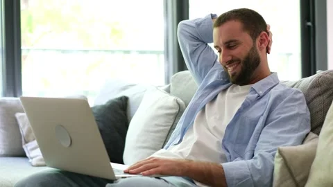 Relaxed young man using a laptop while sitting on the couch Stock Footage 335588569