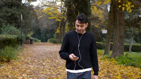 Relaxed young man walking in the park listening music- slow motion Stock-Footage 87346256