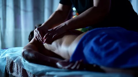Relaxing back massage using oil. The light of the garlands creates an atmosphere Stock Footage 301305376