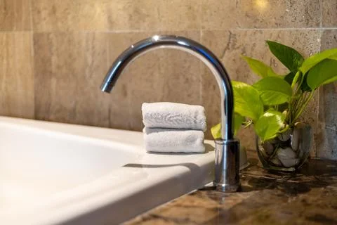 Relaxing bathroom setting featuring a sleek faucet, plush towels, and a fresh Foto stock
