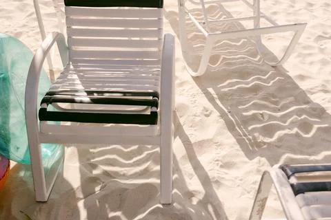 Relaxing beach chairs casting shadows on soft sand during a sunny day at the Foto stock