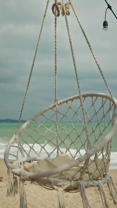 Relaxing beach hammock chair gently swaying by turquoise ocean waves with c.. 库存影片 334906053