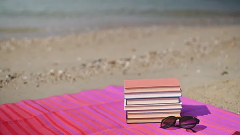 Relaxing Beach Read: Books, Sunglasses, and Splashing Waves Stock Footage 250471953