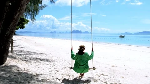 Relaxing on a beach swing with stunning ocean views in a tropical paradise Vidéo 329282540