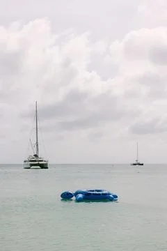 Relaxing on blue float in serene ocean with sailboats in the distance on a Stock-Fotos