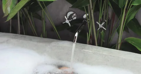 Relaxing Bubble Bath with Running Water in Concrete Tub and Tropical Vibes Stock Footage 289540544