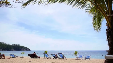 Relaxing on Chaise Longue under Palm Tree on Remote Beach. Stockbeeldmateriaal 42727490