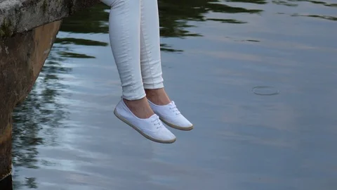 Relaxing Female legs dangle over water Stock Footage 91870060