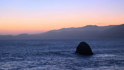 Relaxing footage of a setting sun behind the horizon of mountains above the Stock Footage 127296338