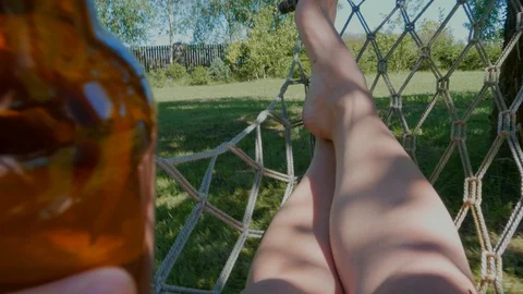 Relaxing in a hammock with a bottle of beer Stock Footage 93549377