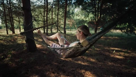 Relaxing on a hammock in the woods while using a smartphone Stock Footage 341464965