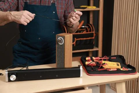 Relaxing hobby. Senior man testing portable bluetooth speaker in workshop, .. Stock Photos
