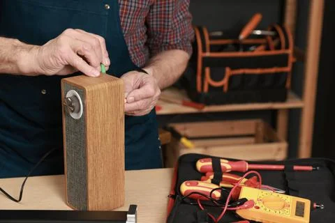 Relaxing hobby. Senior man testing portable bluetooth speaker in workshop, .. Stock Photos