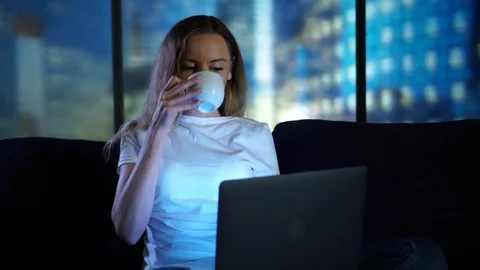 Relaxing at home, drinking tea coffe using laptop, searching social media, at Stock Footage 95199252