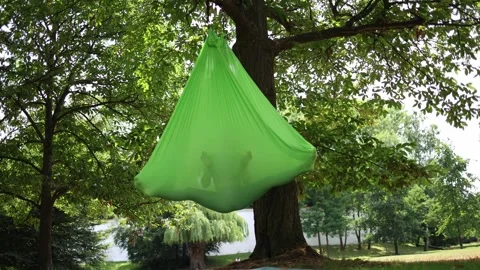 Relaxing inside a green aerial hammock in the forest during a wellness travel re Stock Footage 313175702
