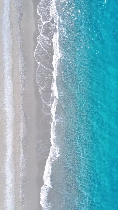 Relaxing Ocean Waves Gently Crash on Sandy Beach Under Clear Blue Skies at Stock Footage 317750878