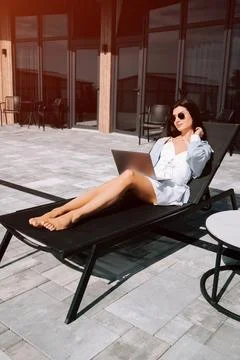 Relaxing by the pool while working on a laptop under the sun Stock Photos