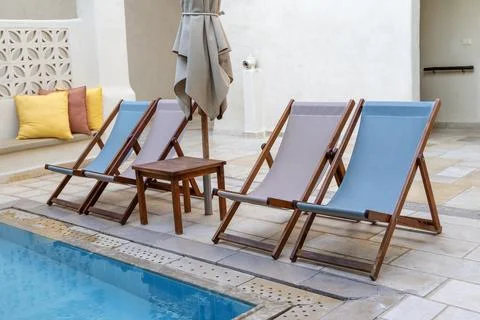 Relaxing Poolside Chairs with Table and Umbrella Stock Photos