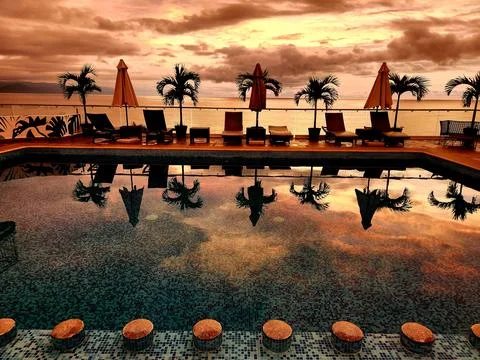 Relaxing poolside with sunset reflections over the water in a tropical paradi Stock Photos