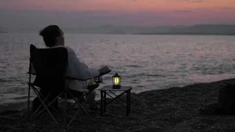 Relaxing by the seashore at sunset with lantern light Stock Footage 303383126