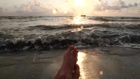 Relaxing at sunset on a sandy beach with gentle waves and a distant boat Vidéo 284480461