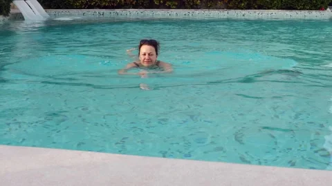 Relaxing swim in clear pool under warm sun in a serene setting Stock Footage 306412515