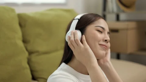 Relaxing time on sofa. Beautiful young asian woman lay down on sofa and listenin Stock Footage 158922012