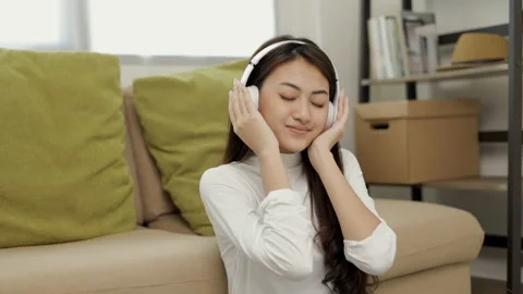 Relaxing time on sofa. Beautiful young asian woman lay down on sofa and listenin Stock Footage 159850469