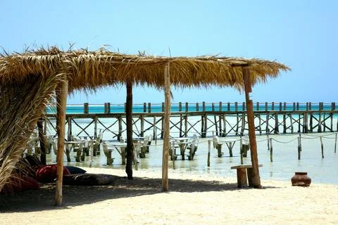 Relaxing Under a Sunshade on Paradise Island With Wooden Pier and Serene Re.. Stock Photos