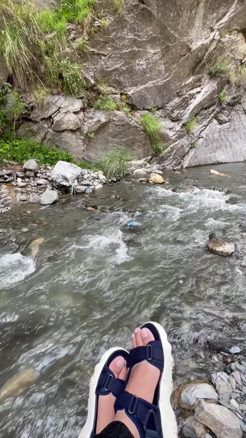 A relaxing vertical video featuring feet resting beside a flowing mountain  스톡 동영상 343612258