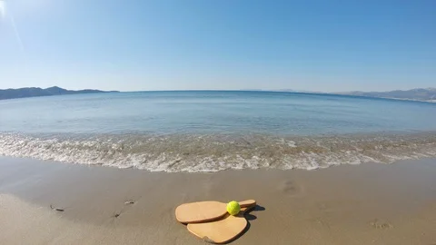 Relaxing view of clear waves calmly washing a beach tennis racket Video stock 130121537