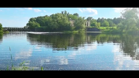 Relaxing view of a river with trees and a building under blue sky on a sunny day Stock Footage 326114904