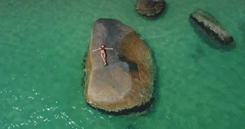 Relaxing on a warm rock by the ocean while enjoying the sunlight and clear Stock Footage 308522773