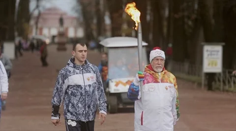 Relay race Olympic flame in Peterhof, Saint Petersburg. Retired torchbearer walk Stock Footage 62878270