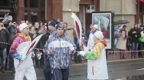 Relay race Sochi Olympic torch in Saint Petersburg. Aged female pass flame to Stock Footage 62744660