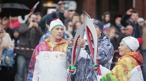 Relay race Sochi Olympic torch in Saint Petersburg. Aged woman pass flame to man Stock Footage 62744661