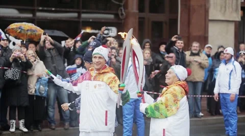 Relay race Sochi Olympic torch in Saint Petersburg. Aged female torchbearer pass Stock Footage 62744665
