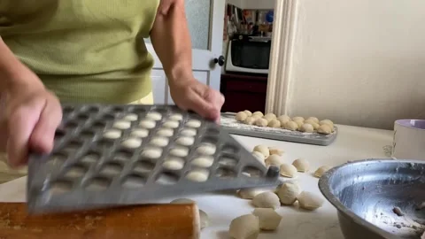 Releasing dumplings from mold onto table with ready dumplings in the background Stock Footage 315345920