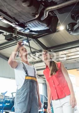 Reliable auto mechanic checking the car of a woman in a modern repair shop Stock Photos