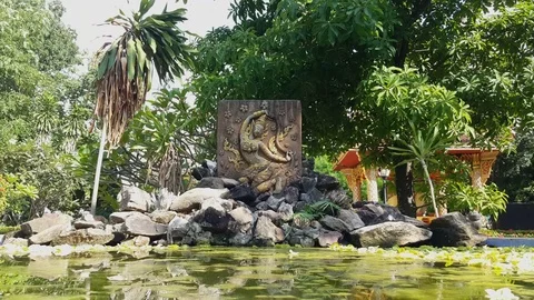 Relief of happy Indian deva dances, pile of rocks in pond, Wat Inpeng courtyard Stockbeeldmateriaal 80679330
