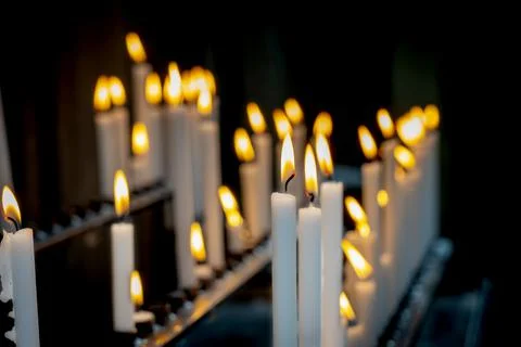 Religion background with burning white candles on fireplace at Church Stock Photos