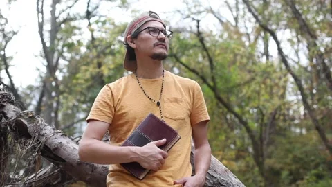 A religious man contemplates the Bible while outside in a park Stock Footage 142225436