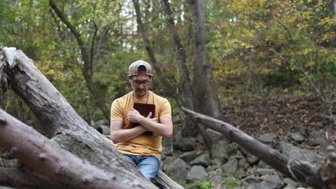 A religious man contemplates the Bible while outside in a park Stock Footage 142225440
