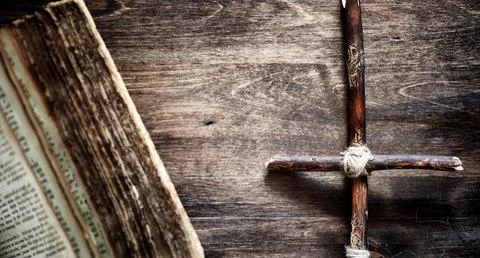 Religious old book on a wooden table. A religious cross tied with a rope an.. Photos