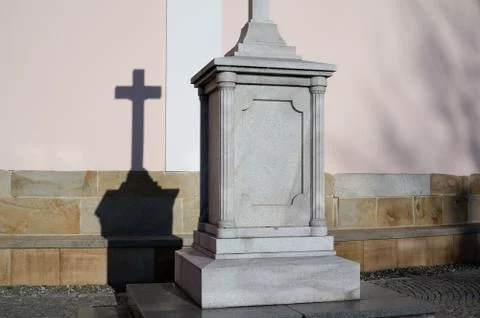 Religious sculpture of cross on solid stony pedestal Stock Photos