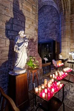 Religious statue and candles inside a historic church in Guerande, Guerande.. Stock Photos
